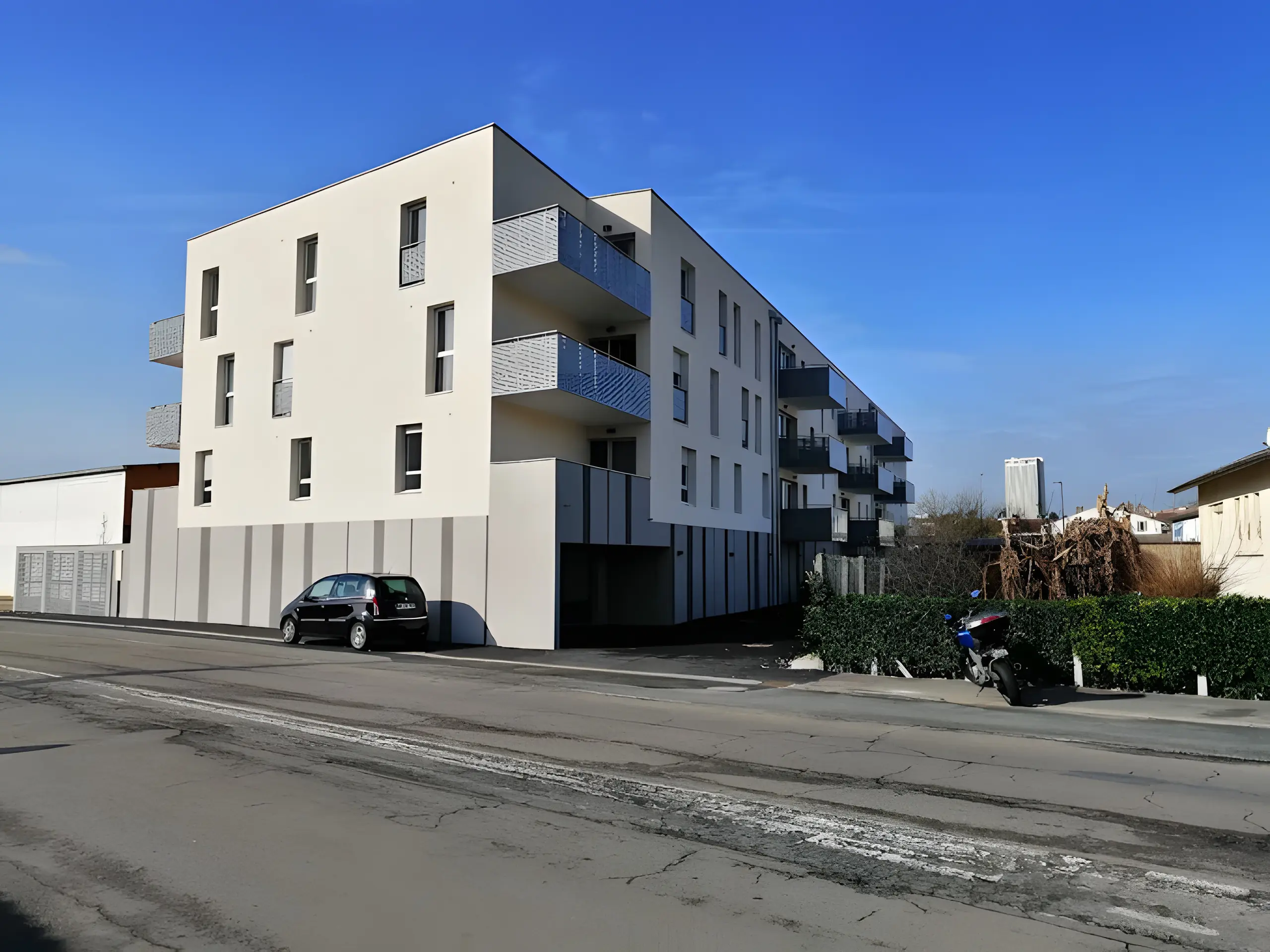 Immeuble neuf de trois étages à façade blanche et balcons gris