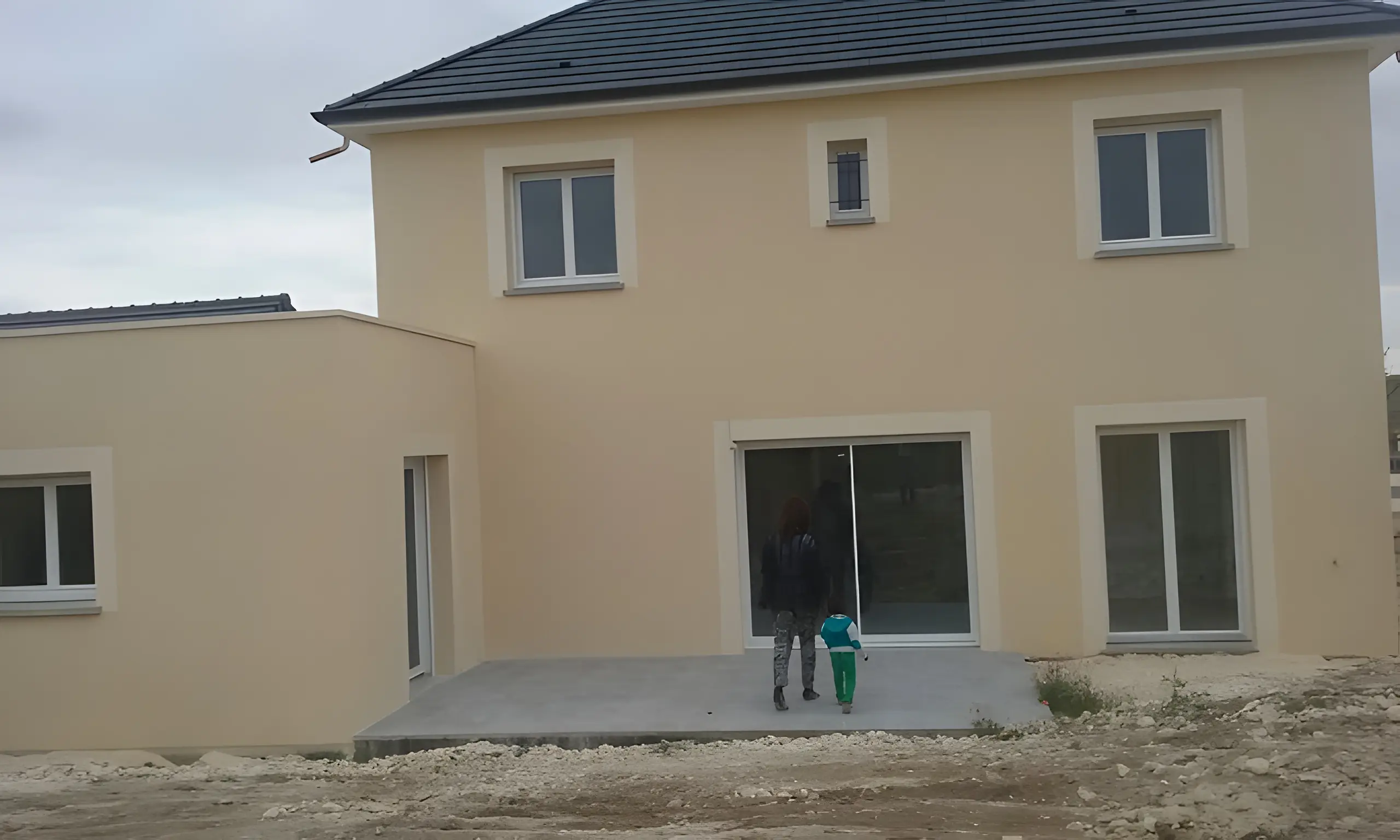 Maison à étage enduite, fenêtres blanches et baie vitrée posées par Menuiserie Confiance