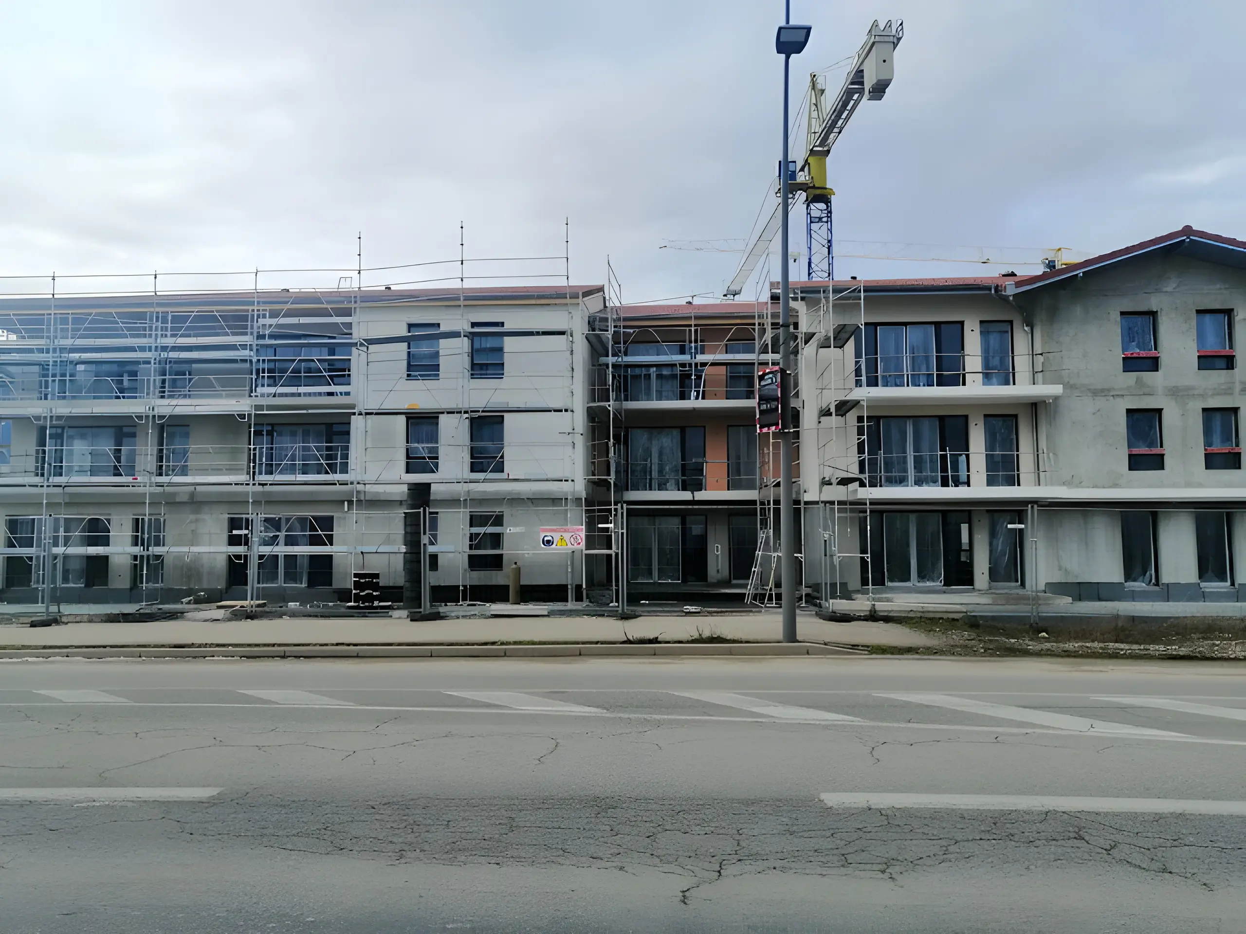 Résidence en construction sous échafaudages, grue en arrière-plan
