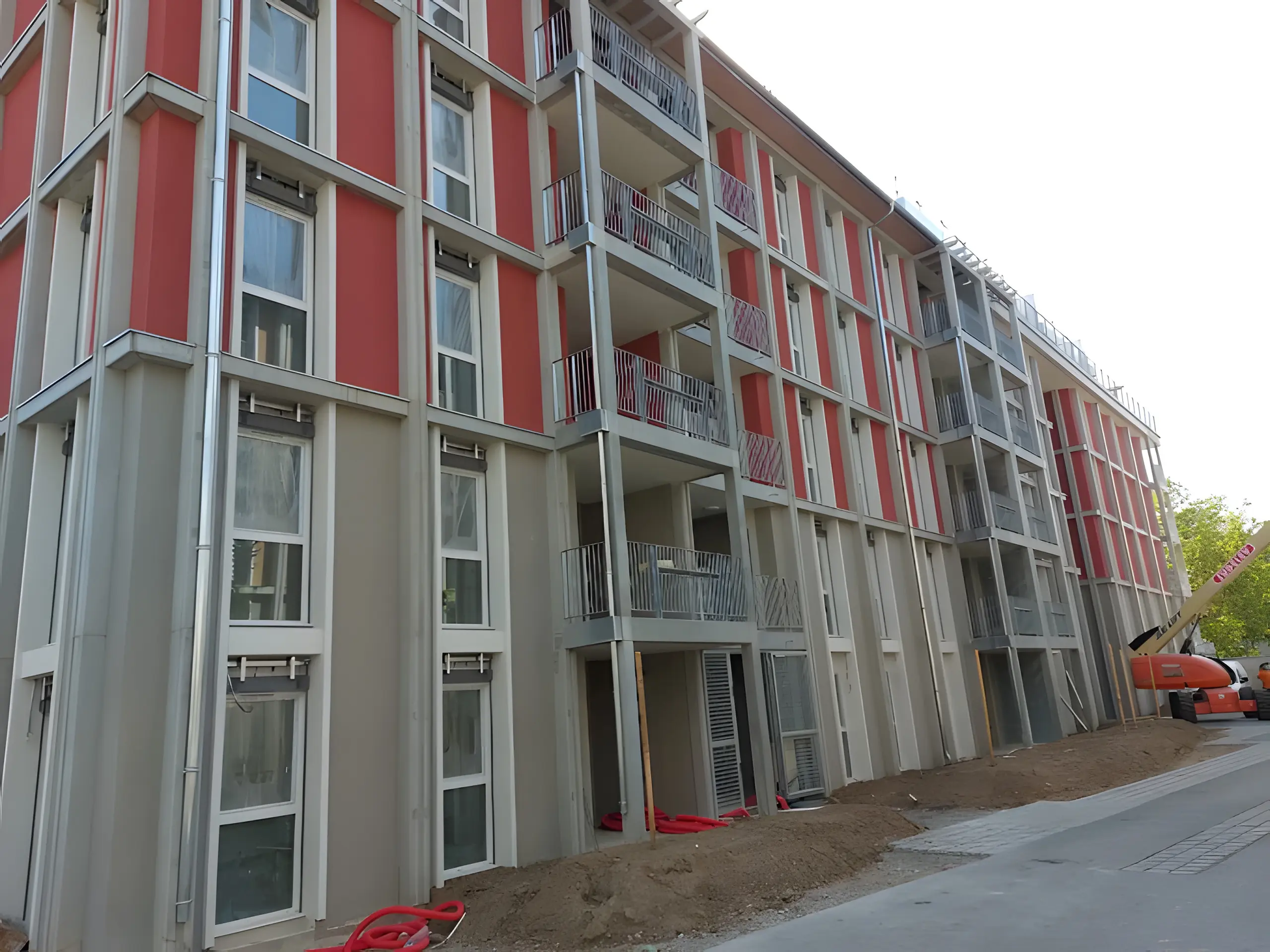 Grande résidence neuve aux façades rouges et grises, rangées de fenêtres