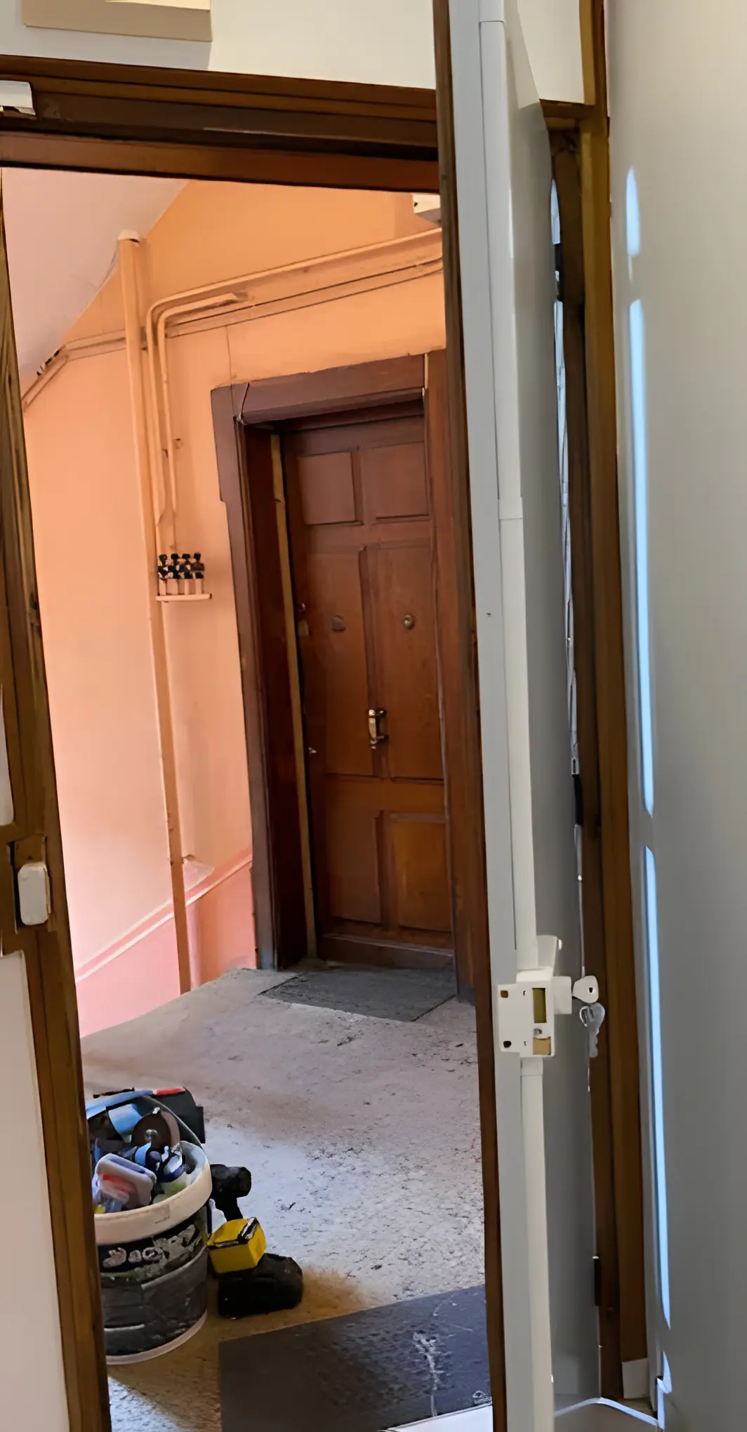 Porte d’appartement ouverte sur le palier : serrure en applique blanche et ses tringles sur le chant